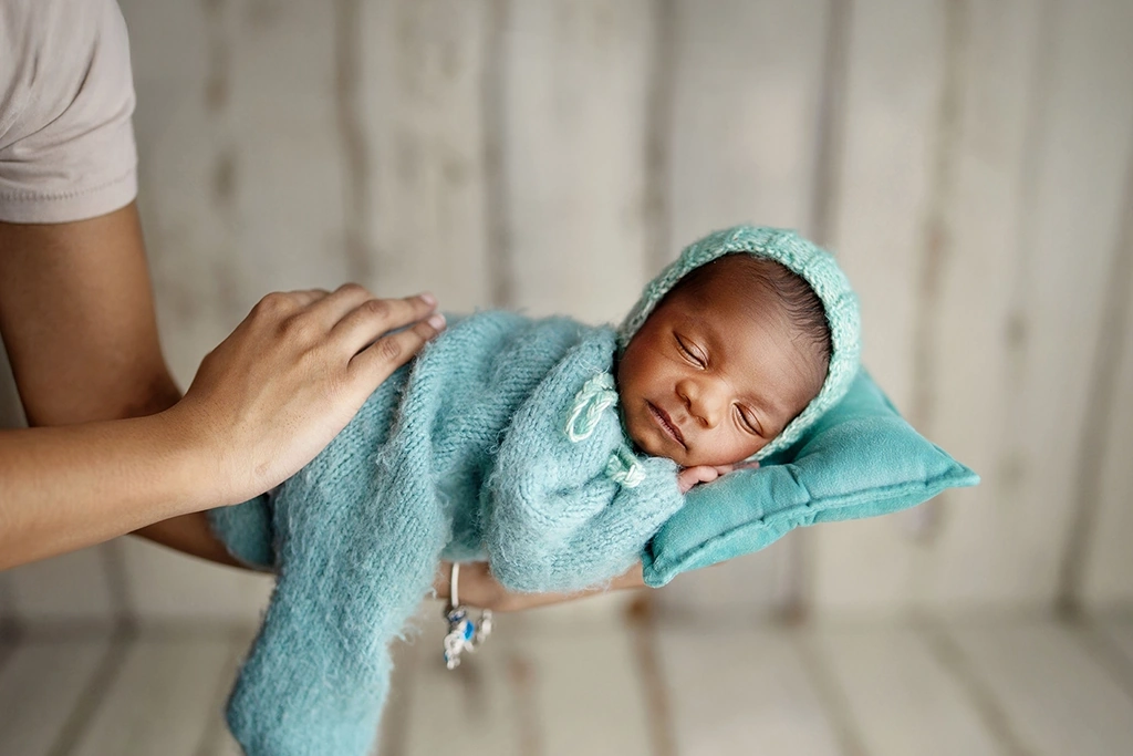Parent gently holding a sleeping newborn baby during a family newborn photography session in Enfield, North London