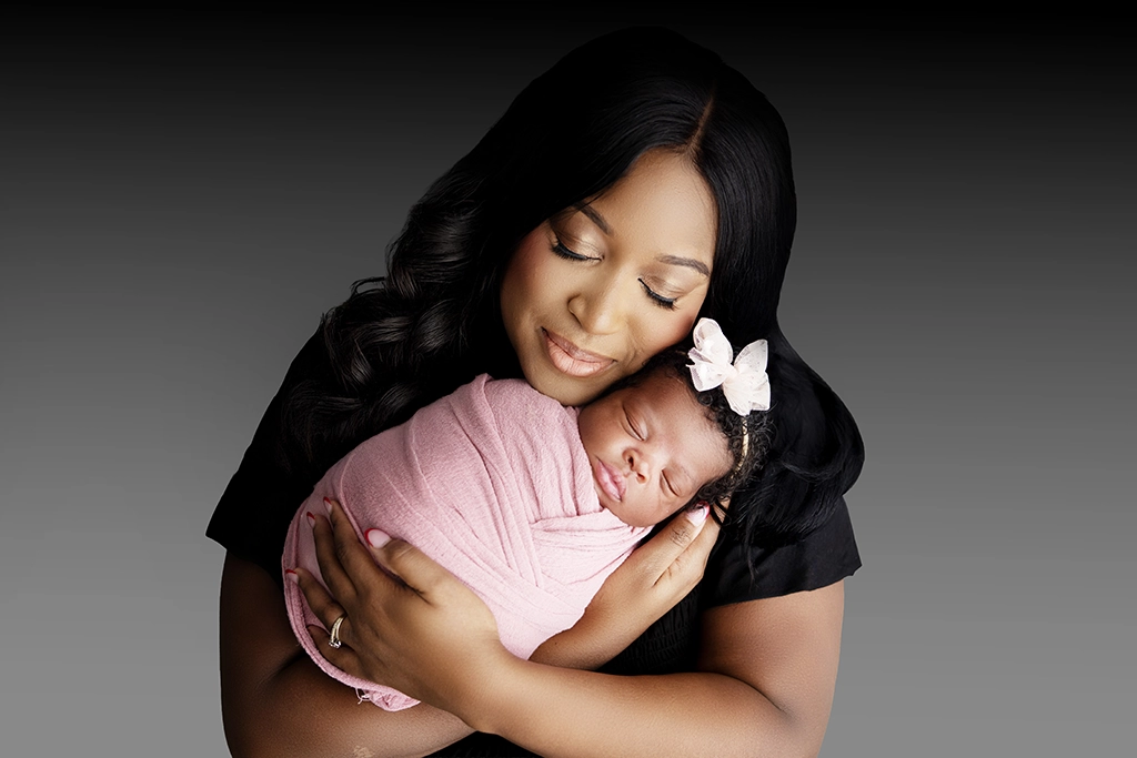 Mother holding her sleeping newborn baby in her arms during a newborn photography session in Enfield