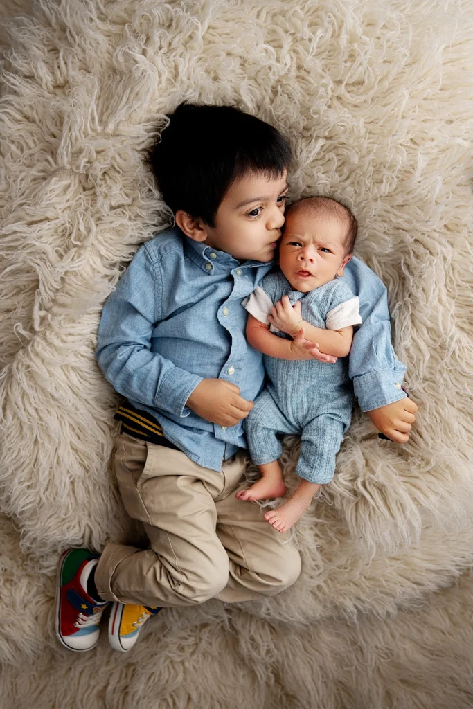 Older brother cuddling his newborn sibling during a newborn photography session in Enfield, North London