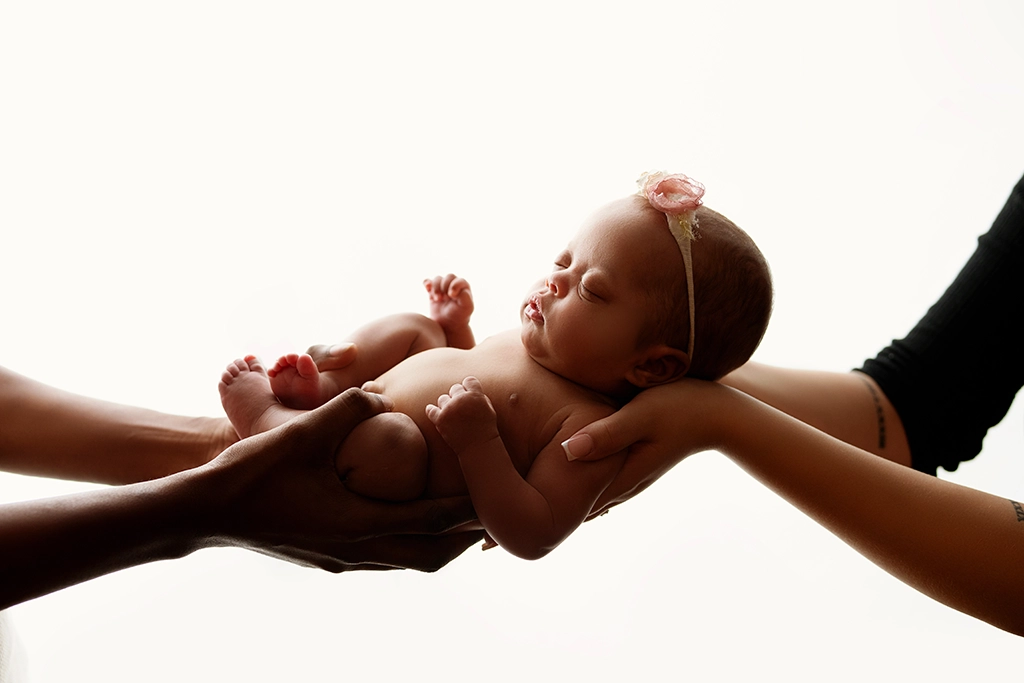 Sleeping newborn baby gently held in parents' hands during a newborn photography session in Enfield, North London