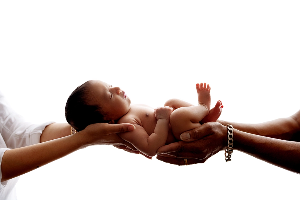 Newborn baby gently held in parents’ hands during a newborn photography session in Enfield, North London