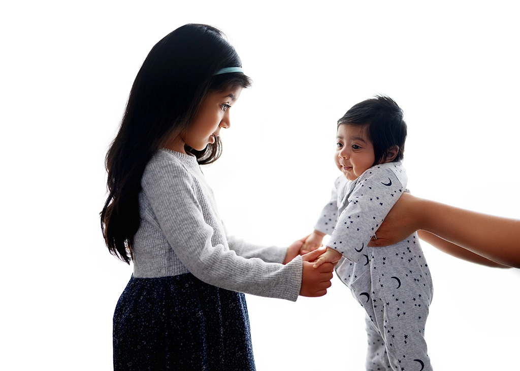 Older sister meeting her newborn sibling during a newborn photography session in Enfield, North London