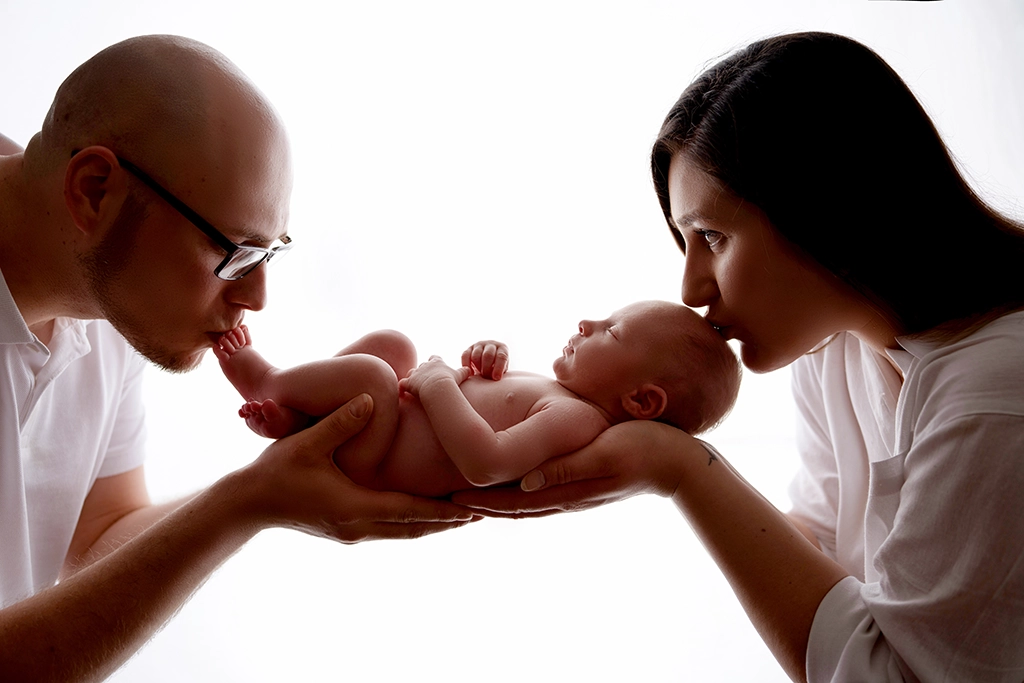 Parents gently holding and kissing their newborn baby during a newborn family photography session in Enfield, North London