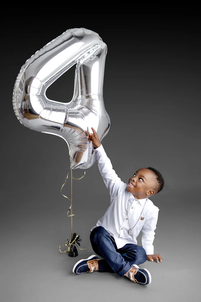 Child holding a number balloon during a birthday photography session in Enfield