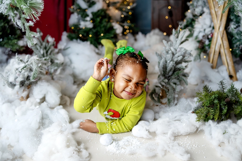 Young child playing in artificial snow during a Christmas photography session in Enfield, North London