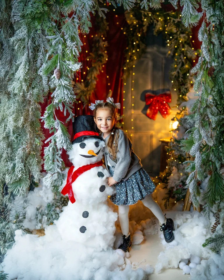 Young girl posing with a snowman during a Christmas photography session in Enfield, North London