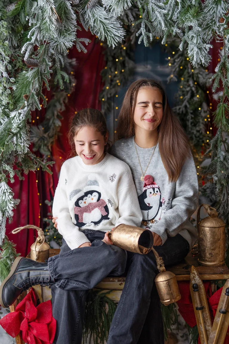 Two sisters wearing festive Christmas jumpers during a Christmas photography session in Enfield, North London
